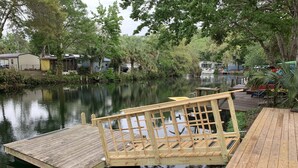 A wooden dock extending into a calm river with a small bridge over it. - Weeki Wachee Pirate House (Spring Hill)