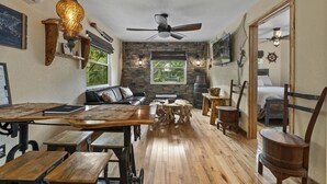 A cozy room with a wooden dining table, benches, a sofa, and a ceiling fan. - Weeki Wachee Pirate House (Spring Hill)