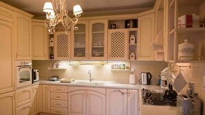 Une cuisine avec des meubles blancs, un lustre, un évier, une cuisinière et un grille-pain.