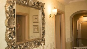 Une salle de bain avec un grand miroir décoratif, un luminaire fixé au mur et un tableau encadré accroché au mur.
