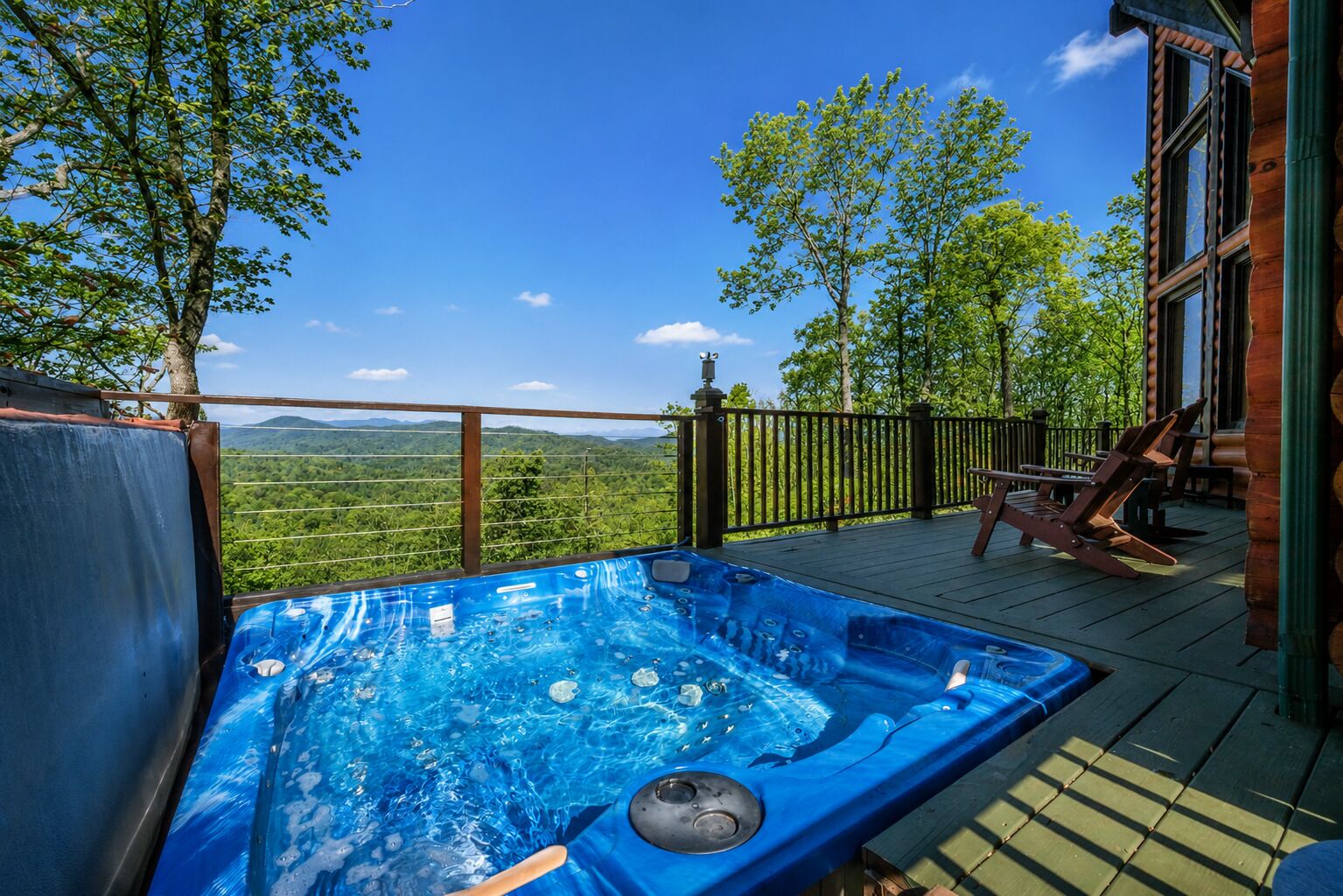 Ett bubbelbad på en terrass med utsikt över en skog och berg.