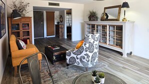 A living room with a sofa, a patterned armchair, a small table, a cabinet, and a hanging light fixture. - Peaceful 55+ Retreat, Fully Stocked, Ideal for Long Stays, Updated Home (Sun City)