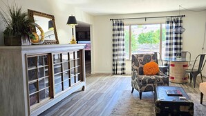 A living room with a fireplace, a patterned armchair, a small table, and a view through a window. - Peaceful 55+ Retreat, Fully Stocked, Ideal for Long Stays, Updated Home (Sun City)