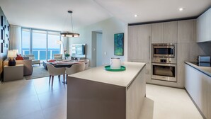 A modern kitchen with a central island, built-in appliances, and a dining area with a view of the sea.