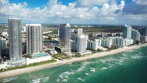 A coastal cityscape with high-rise buildings, a beach, and a clear sky.