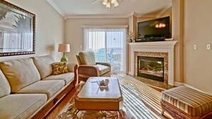 Ein Wohnzimmer mit Sofa, Sesseln, Couchtisch, Kamin, Fernseher und Deckenventilator.