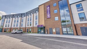 Un hôtel moderne, reconnaissable à son grand panneau « Premier Inn », doté de grandes fenêtres et disposant d’un parking.