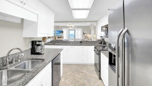 Eine moderne Küche mit weißen Schränken, Granit-Arbeitsplatten, Edelstahlgeräten und einem Oberlicht.