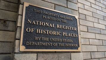A plaque on a brick wall stating the property is on the National Register of Historic Places by the U.S. Department of the Interior.