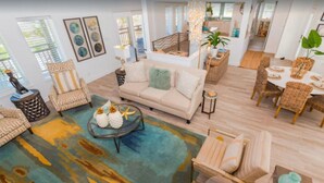 A spacious living area with a large sofa, a coffee table, and a dining table set with chairs. There are decorative pillows and a starfish on the coffee table. - Sandcastle Beach House, Ocean Views, 5Bed 4.5Bath, Huge Outdoor Private Pool (Port Aransas,)