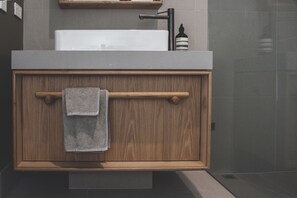 A bathroom with a wooden vanity, a towel hanging on the towel bar, and a bottle of liquid soap on the countertop. - The Retreat B&B, offgrid luxury (Buxton)