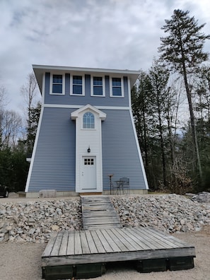 A two-story building with a white door and multiple windows. - Three-story Canadian Lighthouse (Fryeburg)