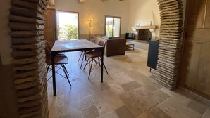 Een eethoek met een grote tafel en stoelen, een open haard en een stenen boog.
