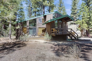 Experience the charm of a historic cabin-style building with a green roof and wooden deck, surrounded by a secluded wooded area.