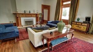 A living room with a fireplace, sofas, a coffee table, and a cabinet. - Mt Vernon Villa (Waipukurau)