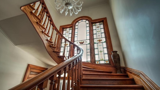 A wooden staircase with a glass railing, leading to a room with stained glass windows. - Mt Vernon Villa (Waipukurau)