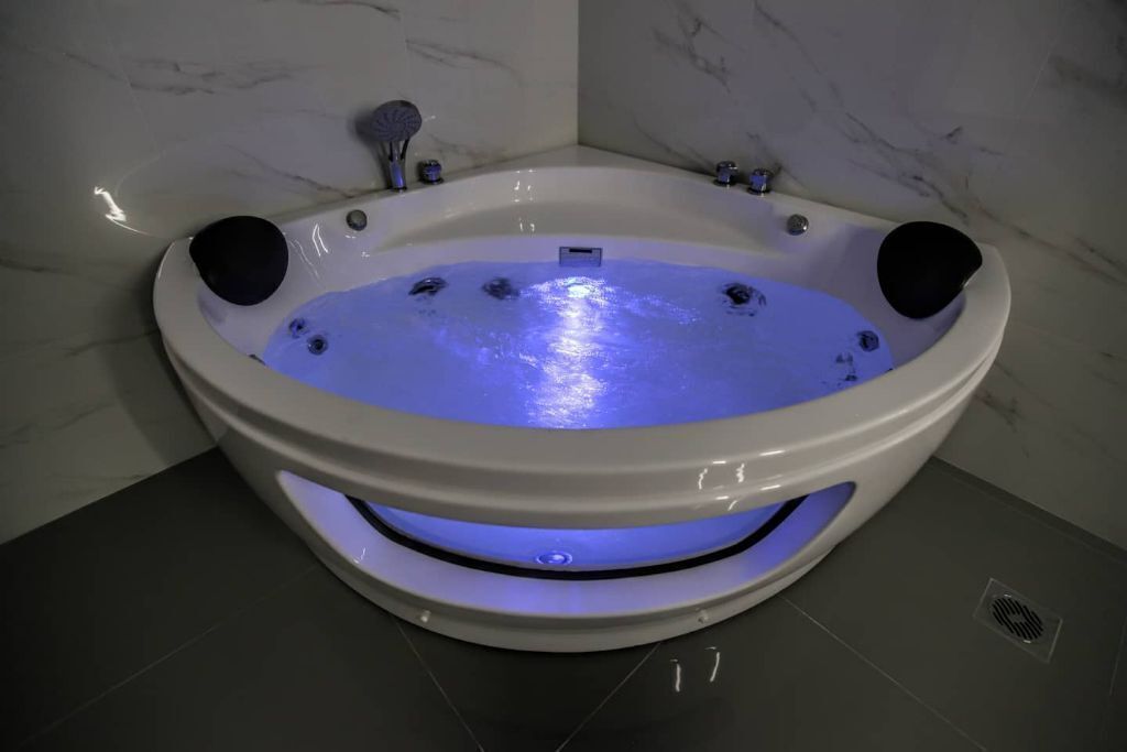 A modern, oval-shaped hot tub with a built-in seat and a blue light feature.