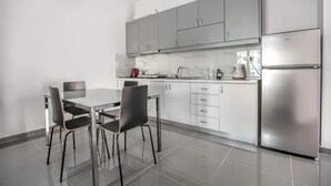 Una cocina moderna con armarios grises, un refrigerador de acero inoxidable y una mesa de comedor con sillas.