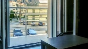 Habitación con un amplio ventanal que ofrece vistas a un estacionamiento y edificios.