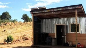 A small, rustic cabin with a wooden porch and a corrugated metal door. - While not a hotel, the Feather Trailer provides a relaxed, peaceful retreat in nature with the warmth and convenience you need for a memorable outdoor getaway. (Monticello)