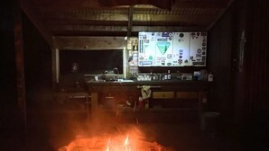 A room with a fireplace, a table, and a wall-mounted screen displaying various icons. - While not a hotel, the Feather Trailer provides a relaxed, peaceful retreat in nature with the warmth and convenience you need for a memorable outdoor getaway. (Monticello)
