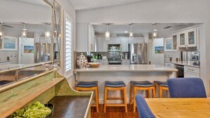 Una cocina moderna con una isla central, taburetes de bar y una mesa de comedor.