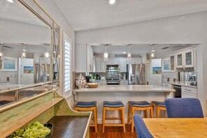A modern kitchen with a central island, bar stools, and a dining table.