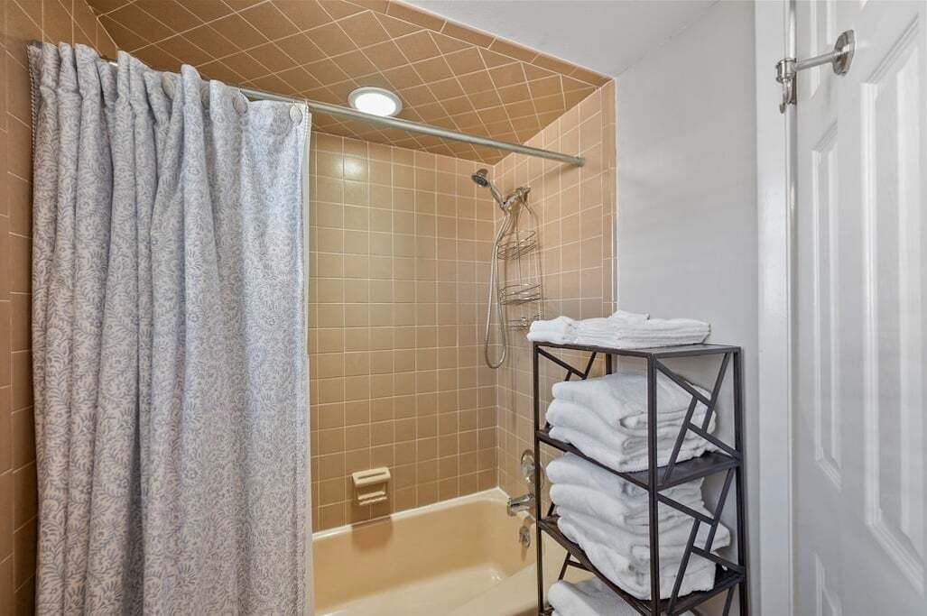 A bathroom with a shower, a towel rack, and a bathtub.