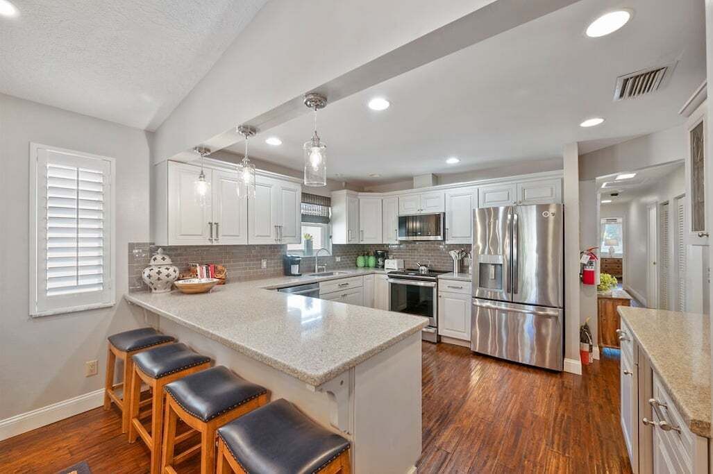 A modern kitchen with white cabinets, stainless steel appliances, and a central island with stools.