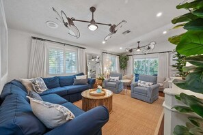 A living room with a blue sofa, striped armchairs, a round coffee table, and ceiling fans.
