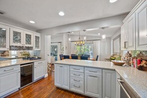 A spacious kitchen with a central island, built-in cabinetry, and a dining area with chairs.