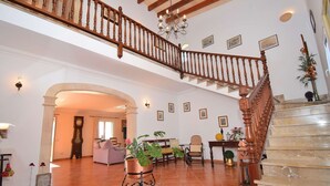 A spacious living area with a grand staircase, a chandelier, and a large clock. - Can Claret Gran 176 wonderful villa with private pool, large terrace, air conditioning and WiFi (Cas Concos)