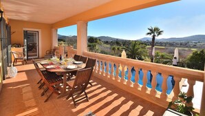 A terrace with a table set for dining, a view of the countryside, and a balcony railing. - Can Claret Gran 176 wonderful villa with private pool, large terrace, air conditioning and WiFi (Cas Concos)
