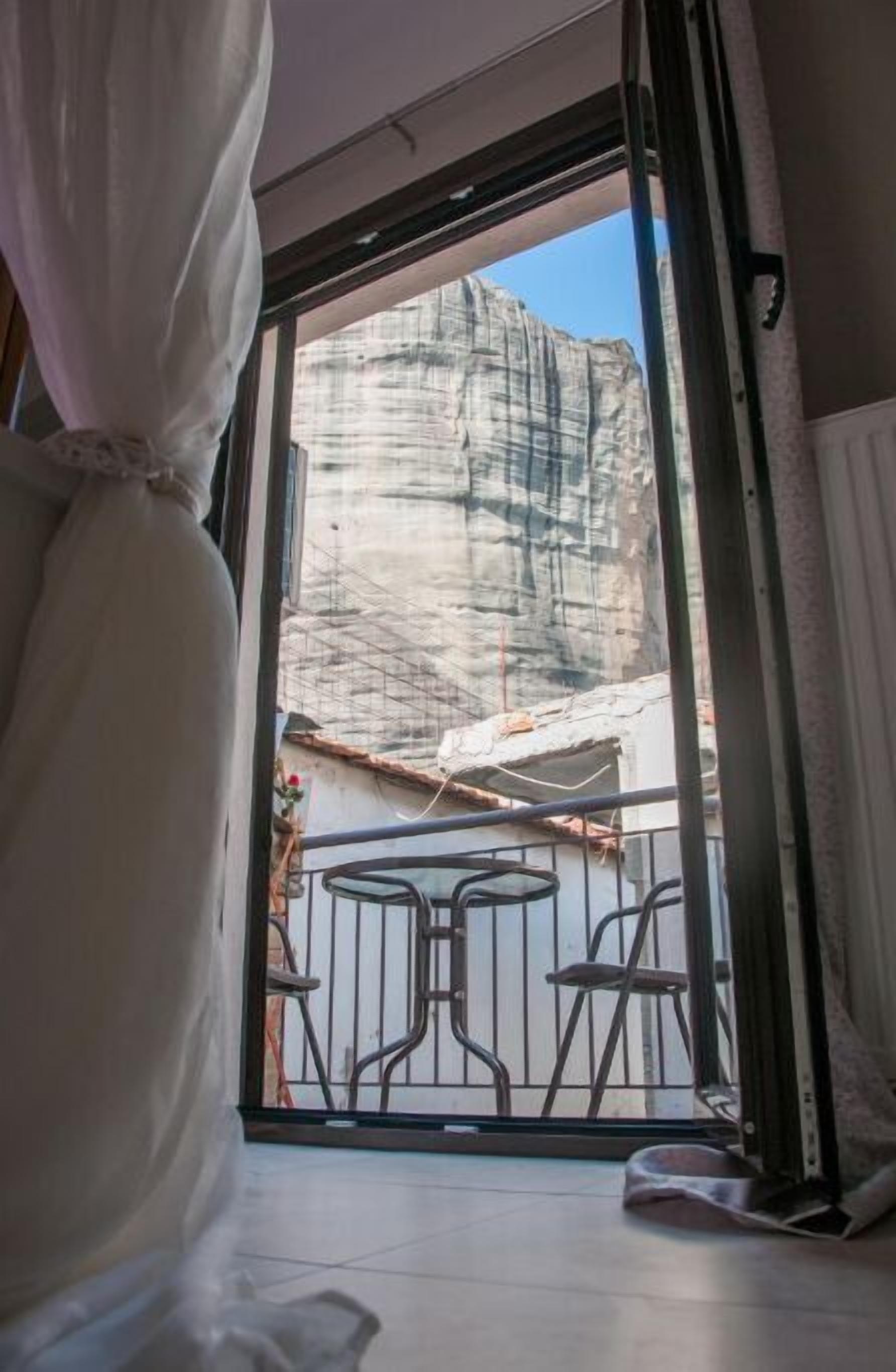 A room with a large window, a curtain, and a view of a rocky landscape outside.
