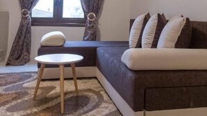 Un salon moderne avec un canapé, une petite table ronde et un tableau accroché au mur.