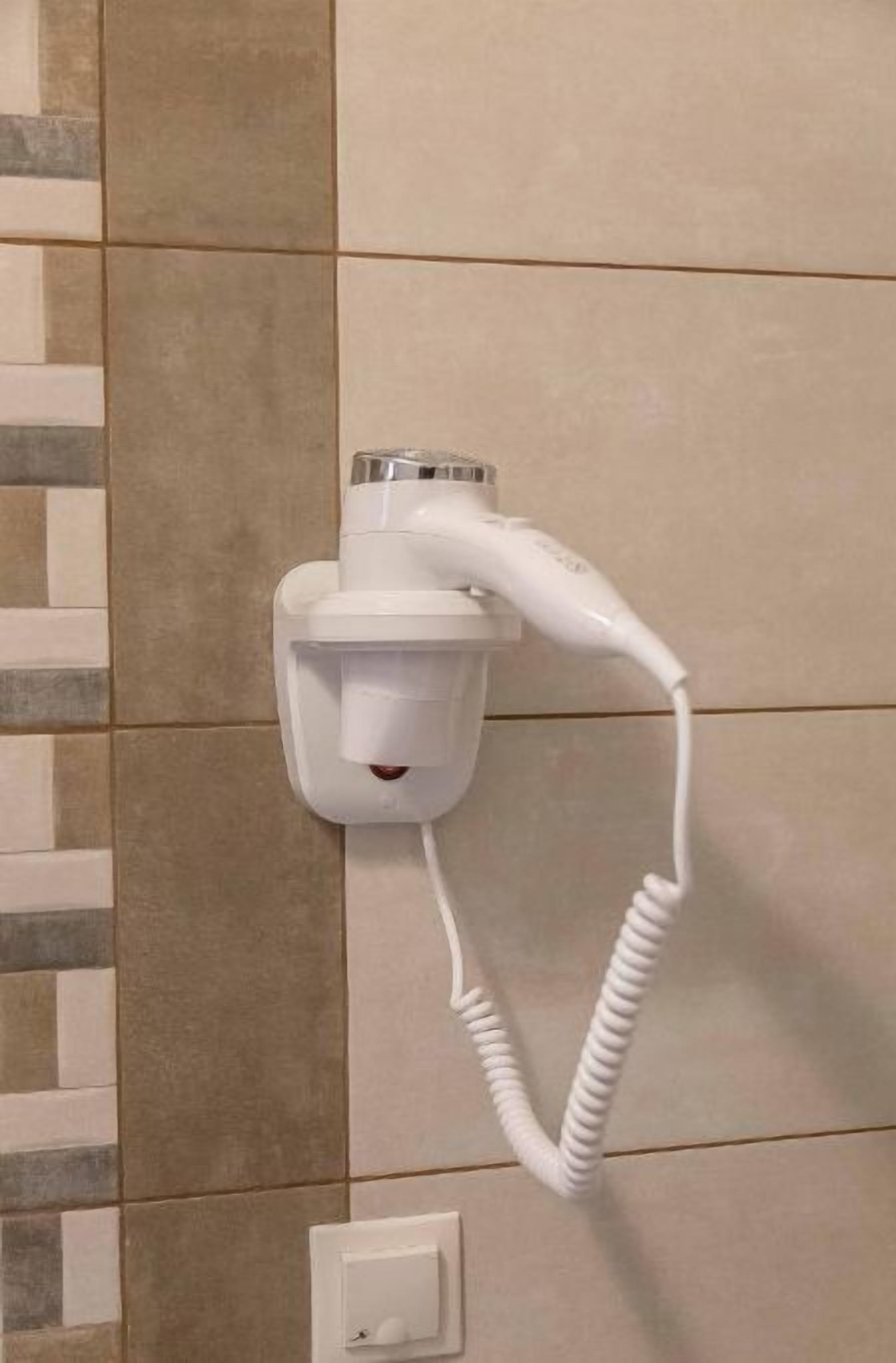 Telefone branco fixado na parede, com fio enrolado.