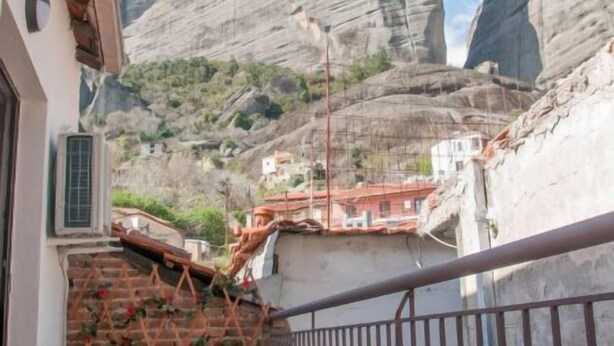 Un balcon offrant une vue sur des montagnes rocheuses, un sol carrelé et une rambarde en métal.