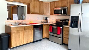 Una cocina moderna con armarios de madera, electrodomésticos de acero inoxidable, lavavajillas y dispensador de agua.