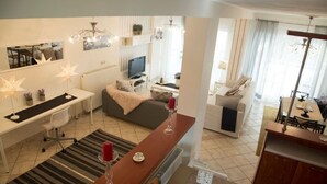 Uma sala de estar moderna com um sofá, uma mesa de jantar e uma televisão. Há iluminação decorativa e uma lareira.