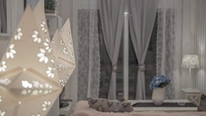 Uma sala de estar aconchegante com sofá, abajur e um vaso com flores.