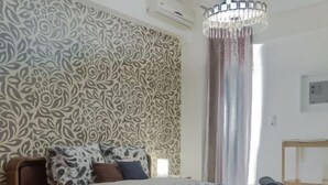 Quarto com colcha estampada, um candelabro e parede decorada.