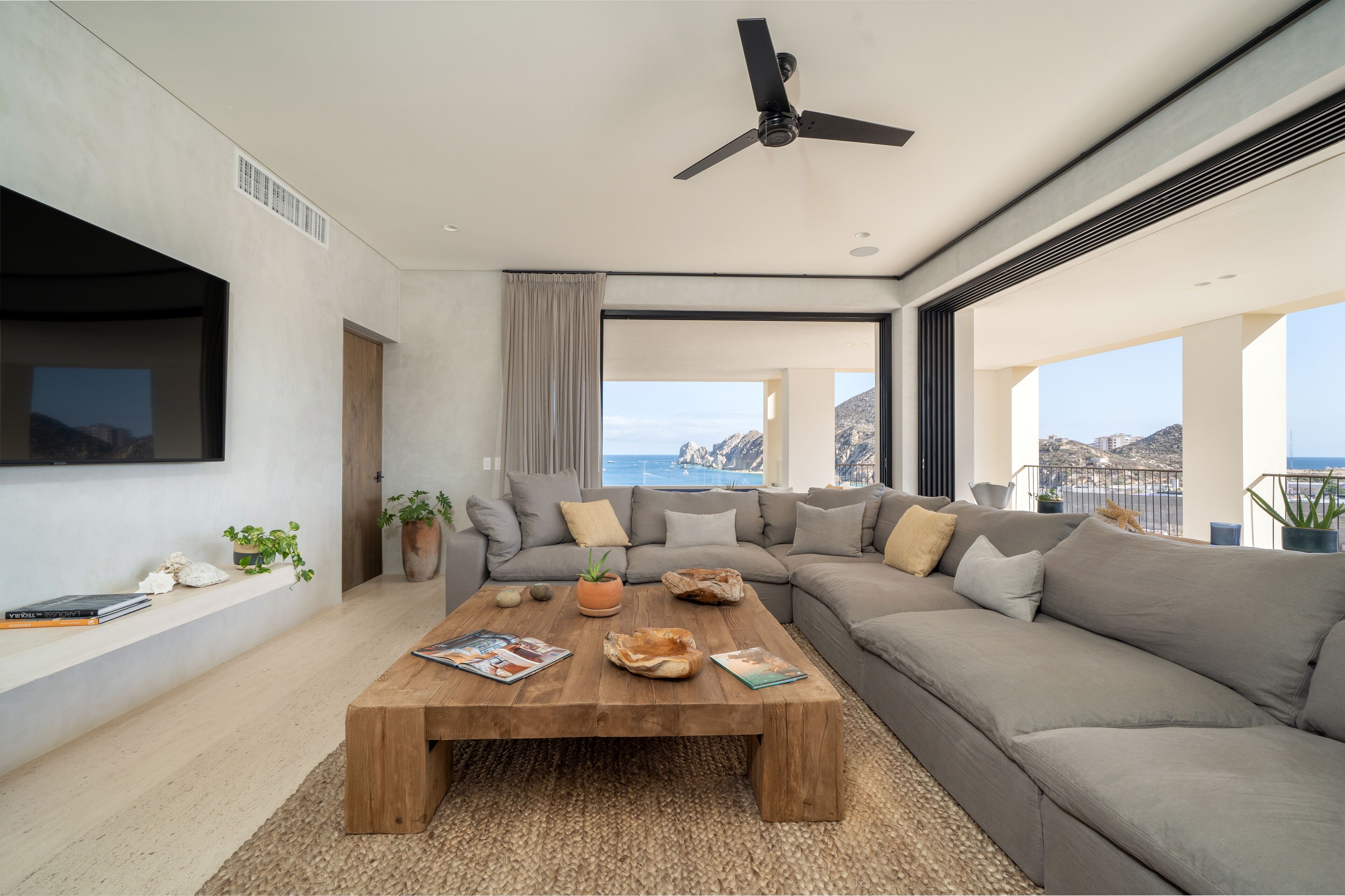 Un salon moderne avec un grand canapé, une table basse en bois et un ventilateur de plafond.