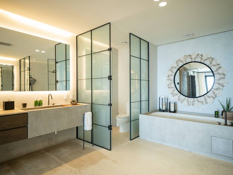A modern bathroom with a glass partition, a large mirror, and a round decorative mirror on the wall.