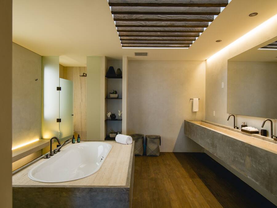 A modern bathroom with a large freestanding bathtub, a double vanity with a large mirror, and a wooden ceiling.
