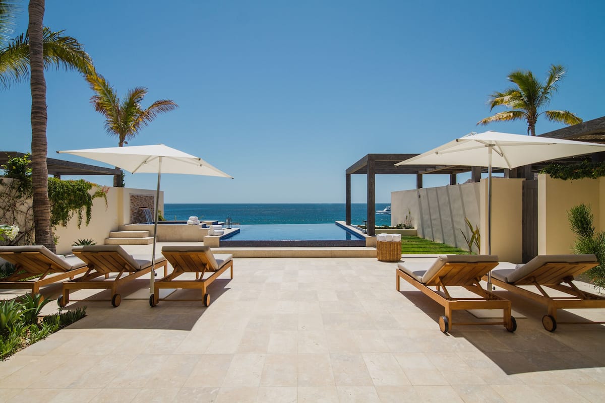 A poolside area with lounge chairs and umbrellas, overlooking the ocean.