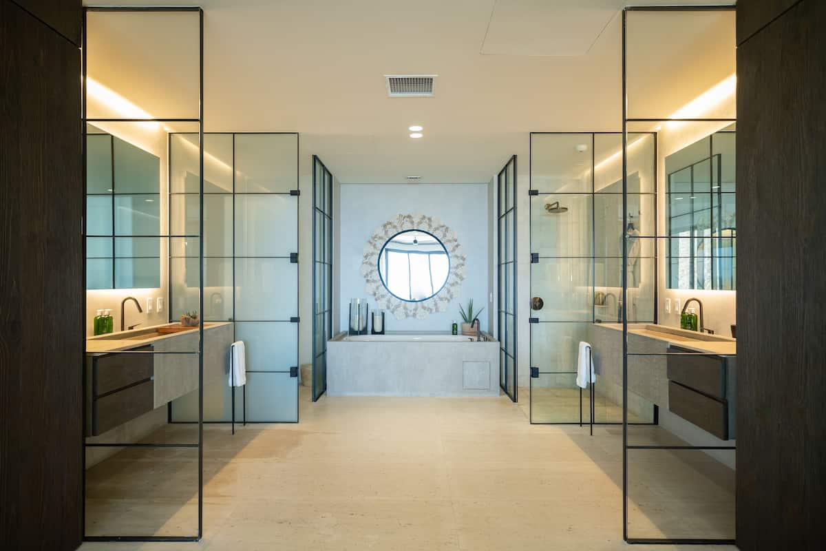 A modern bathroom with a large mirror, a round mirror above the sink, and a central round mirror.