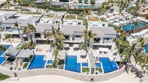 Vista aérea de un complejo turístico con varias piscinas, palmeras y una zona de playa.