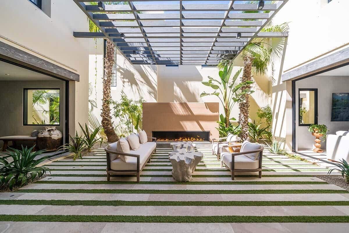 An outdoor living area with a fire pit, sofas, and planters.