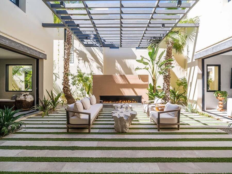 An outdoor living area with a fire pit, sofas, and planters.