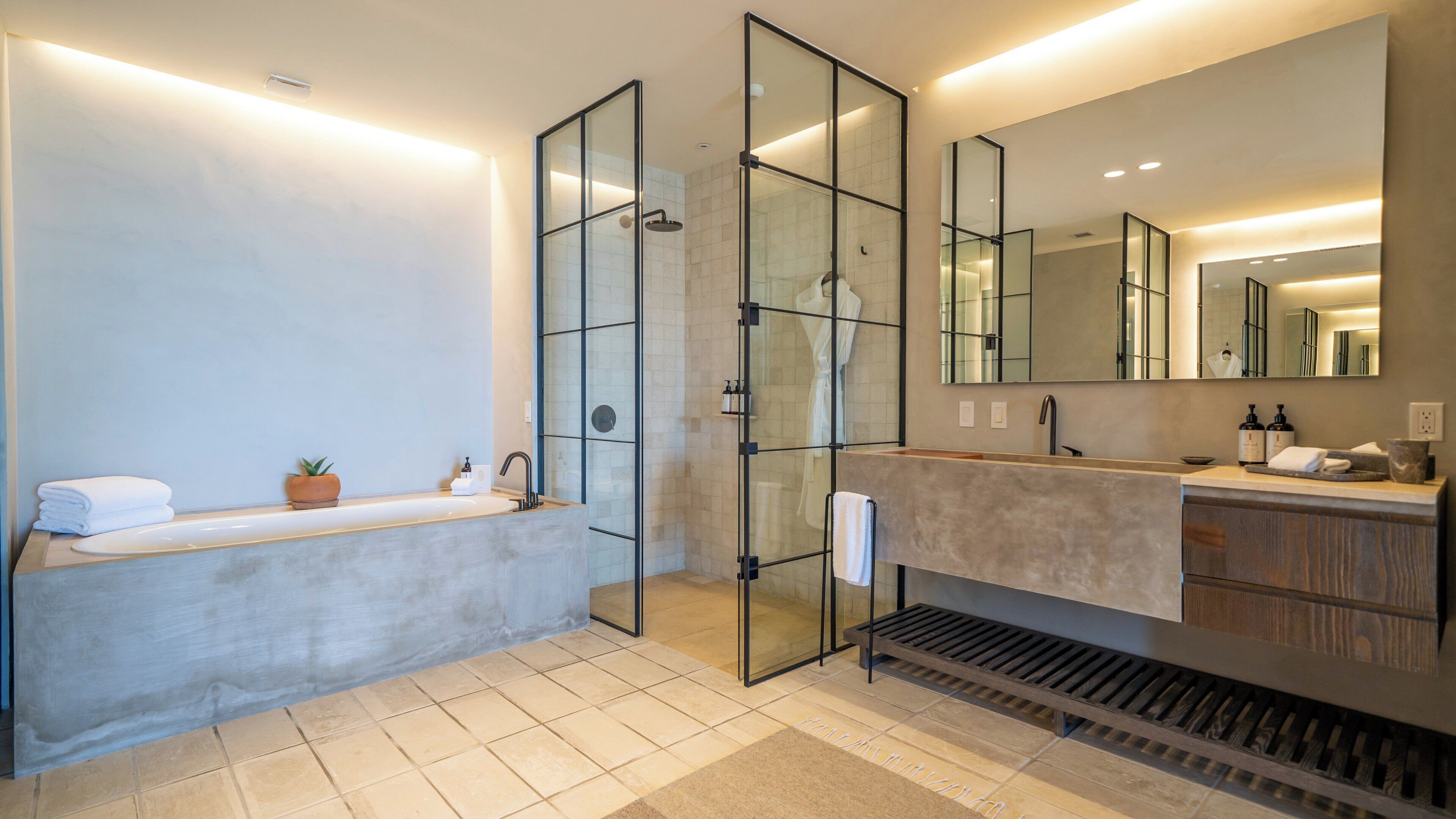A modern bathroom with a glass-enclosed shower, a large mirror, and a vanity with a sink and storage.